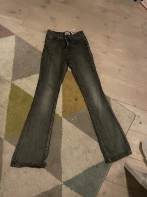Grå bootcut jeans från vero moda - Snygga grå jeans med bootcut-modell och lätt slitna detaljer. Jeansen har en tvättad look och bootcut. Perfekta för en avslappnad och trendig stil.