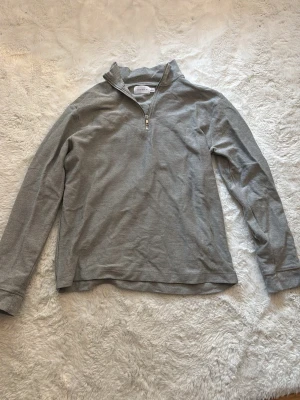 Grå halvzip-tröja från TOPMAN - Snygg grå långärmad tröja från TOPMAN med halvzip och ståkrage. Tillverkad i mjukt material som känns skönt mot huden. Perfekt för lager på lager och enkel att matcha med olika outfits.