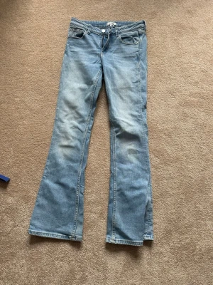 Ljusblå Gina jeans med extra längd! - Säljer ett par ljusblå bootcut jeans med klassisk femficksdesign och normal midja. Jeansen har en lätt tvättad look och vida ben från knät och ner. Perfekta för en avslappnad och trendig stil. Jeansen har också en extra längd, så för mig som är 167 cm kan fortfarande ha dem, alltså längdvis!