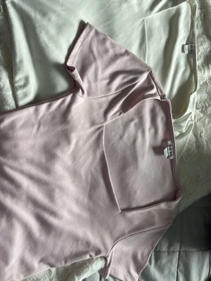 Två toppar från Amisu i rosa och vitt - Säljer två stilrena toppar från Amisu, en i ljusrosa och en i vit. Båda har korta ärmar, fyrkantig ringning och är gjorda i mjuk bomullsmix. Perfekta att matcha med jeans eller kjol för en clean look.