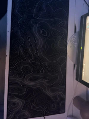 Stor svart musmatta med mönster - Säljer en stor svart musmatta med unikt topografiskt mönster i grått. Perfekt för gaming eller kontor, ger bra glid för musen och täcker en stor del av skrivbordet. Materialet är textil med gummibotten för att ligga stadigt på plats.