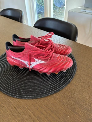 Röda Mizuno fotbollsskor med skruvdobb - Säljer ett par röda Mizuno fotbollsskor, köpta i Italien och använda 3 gånger. Passade inte min fot som jag ville. Har kvitto på skorna.