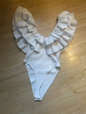 Vit volang body - Säljer denna eftertraktade body från Zara som inte längre går att köpa på hemsidan!! Body är i nyskick. Det finns inga fläckar eller andra defekter. Skriv gärna för fler bilder eller andra frågor🥰🥰