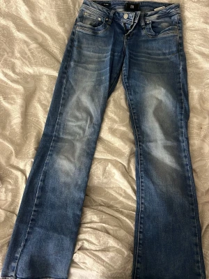 Blå bootcut jeans från LB - Snygga blå bootcut jeans från LB med slitningar och ljusare partier framtill. Klassisk femficksmodell med dragkedja och knapp. Jeansen har en något utsvängd passform nedtill och är tillverkade i denim med en skön känsla. Som nya jättefina❤️❤️