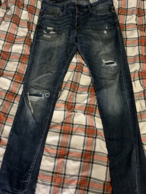 Jeans jack&jones - Säljer dessa jeans från jack & jones! Även dessa med otroliga fades och slitningar! (Slitningarna är en del av designen och inte skador) storlek 32/34 Jeansen har inga defekter och är sparsamt använda. Pris 299 kr!