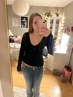 Svart långärmad topp med v-ringning - En enkel och stilren svart långärmad topp med djup v-ringning. Toppen har en tight passform och är perfekt att matcha med jeans. Har bara använt den 1 gång.