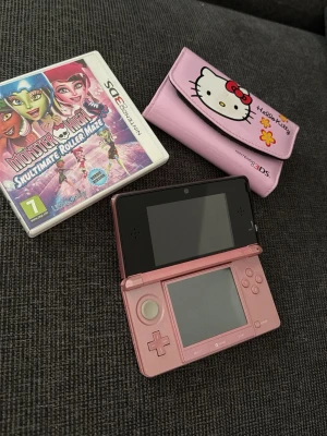 Rosa Nintendo 3DS med Hello Kitty-fodral - Säljer en rosa Nintendo 3DS med matchande Hello Kitty-fodral och spelet Monster High: Skultimate Roller Maze. Konsolen har dubbla skärmar, styrspak och klassiska knappar. Perfekt för dig som gillar portabel gaming och gullig design.