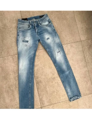 Dondup jeans - Tjena ! Säljer ett par Dondup jeans med slitningar och distressed detaljer på benen. Jeansen är tillverkade i stretchigt denimtyg för en skön passform. Jeansen har Inge defekter förutom en liten lagning som inte synns. Kontakta för mer information 