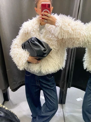 Svart clutch i mjukt skinn - Säljer en svart clutch i mjukt, slätt skinn med puffig form och minimalistisk design. Väskan har en modern look och är enkel att matcha med olika outfits. Perfekt för dig som gillar stilrena accessoarer med trendig känsla.