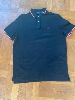 Ralph Lauren vintage piké - Sjukt snygg sällsyntare Ralph Lauren piké i svart färg med vitröda detaljer, väldigt skön och bra passform och Ralph Lauren märker i röd färg broderat på bröstet, storlek L. Inga defekter alls skriv vid frågor😁