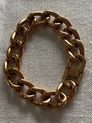 Chunky guldfärgat armband EDBLAD ny Ł 20-22cm unisex - Snyggt chunky armband från EDBLAD i guldfärgad metall. Länkarna är stora och blanka, vilket ger ett statement-utseende. Perfekt för dig som gillar att sticka ut med accessoarer. Låset är diskret och har EDBLADs logga ingraverad.