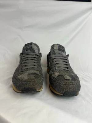 Valentino Rockrunners  - Snygga grå sneakers från Valentino med kamouflagemönster i olika nyanser av grått. Ovandelen är i filtliknande material och skorna har grå skosnören samt beige sula med svart yttersula. Perfekta för dig som vill ha något unikt och trendigt. Storlek 41 och i väldigt fint skick. 