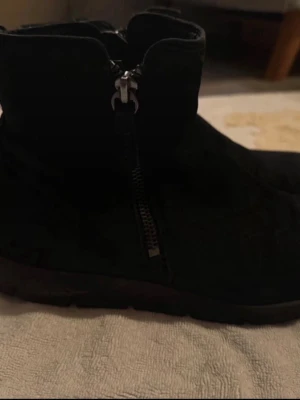 Svarta stövletter från ECCO - Säljer ett par svarta stövletter från ECCO med grov sula och dragkedja på sidan. Skorna är i mockaliknande material och har en stilren, enkel design som passar till många outfits. Perfekta för dig som gillar bekväma och snygga boots.