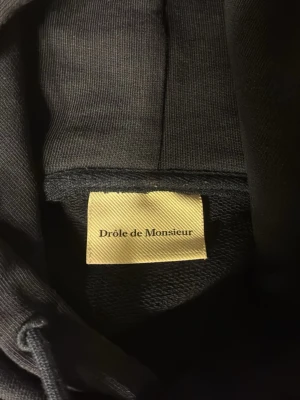 Drôle de Monsieur hoodie - Drôle de Monsieur hoodie med tryck på fram och baksida. Tröjan är mörkblå.  Tröjan är M men är liten i storleken så om du är S är den perfekt! 