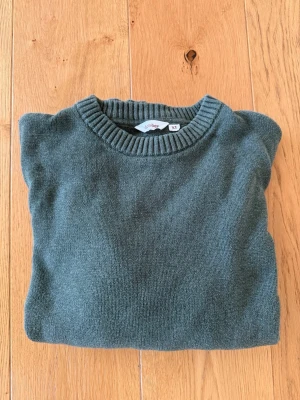 Mörkgrön stickad tröja Uniqlo - Mysig mörkgrön stickad tröja från Uniqlo i storlek XL. Tröjan har rund halsringning, långa ärmar och ribbade muddar vid ärmslut och nederkant. Perfekt för lager på lager och enkel att matcha med jeans eller kjol.
