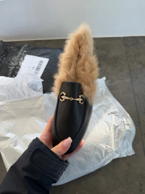 Svarta loafers med päls och gulddetalj - Unika svarta loafers med mjuk beige fuskpäls på insidan och snygg guldfärgad detalj över foten, perfekta nu till våren!💕