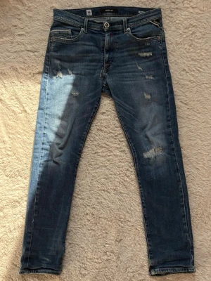 Blå slitna jeans från replay - Säljer ett par blå replay jeans med slitningar och raka ben. Perfekta för en casual stil. Jeansen är i storlek 158/164cm och är i väldigt bra skick✅ Fraktar inom en dag✅ Priset är inte hugget i sten🙂