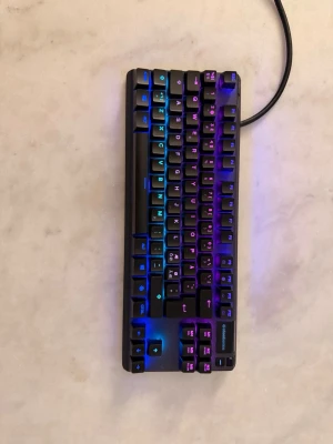 SteelSeries Apex Pro TKL tangentbord - Säljer ett SteelSeries Apex Pro TKL mekaniskt tangentbord med RGB-belysning. Tangentbordet är svart med snygga färgskiftningar i blått, lila och rosa. Kompakt TKL-design och tillverkat i tålig plast och metall. Perfekt för gaming och skrivande. Ny tvättat precis som nytt.