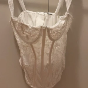 Vit spetskorsett med breda axelband - Säljer en vit korsett med breda axelband, storlek S köpt från Shein. Säljer den för 50kr