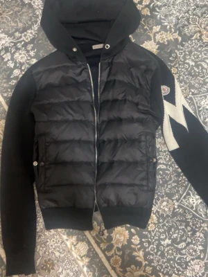 Svart pufferjacka från Moncler - Säljer en svart Cardigan ifrån Moncler, Den är i bra skick 7,9/10, Den är snygg och stilig, har ej sett någon annan ha en sån så om du vill sticka ut och se stilig ut inför våren/sommarn så rekommenderar starkt! Pris ej hugget i sten, vid frågor är det bara skriva.