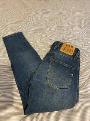 Replay Anbass - Säljer ett par klassiska blå jeans från Replay med snygg gul patch bak i midjan och raka ben. Jeansen har fem fickor och diskreta slitningar för en cool look. Tillverkade i denim med en autentisk tvätt och detaljerade sömmar. W28 L30