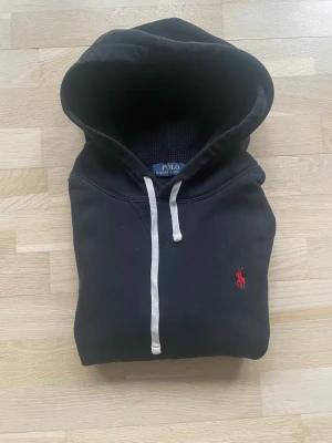 Svart hoodie från Polo Ralph Lauren - Snygg svart hoodie från Polo Ralph Lauren i bra skick. Storleken är large men passar mer som en medium. Hör gärna av er vid funderingar eller frågor!