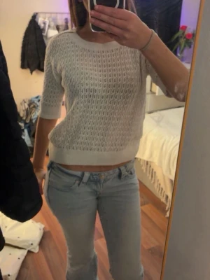 Vit stickad croppad topp - Säljer en vit stickad croppad topp med halvärmar och rund hals. Toppen har ett hålmönster som ger en luftig känsla och är perfekt för varmare dagar. Passformen är normal och materialet känns mjukt mot huden.
