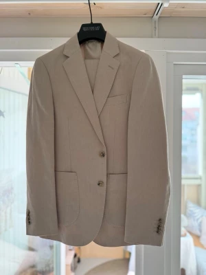 Linnekostym från These Glory Days - Beige kostym ”ARCHER” från These Glory days. Kavaj i storlek 46 och byxor i 44. Använd vid ett tillfälle så praktiskt sett nytt. 