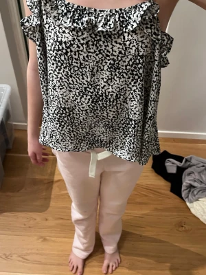 Svartvit blus med volang - Säljer en svartvit blus med abstrakt mönster och volangdetalj vid halsringningen. Blusen  har en luftig passform. Perfekt för dig som gillar en trendig och bekväm stil. Superfin att ha på exempelvis sommaren och väldigt skön. Oanvänd! Öppen för prisförslag❣️