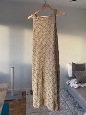 Guldglittrig strandklänning - Genomskinlig virkad klänning som passar på stranden. 