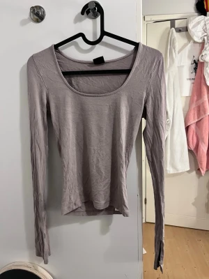 Beige långärmad topp - En enkel och stilren beige topp med lång ärm och rundad urringning. Tillverkad i mjukt material som sitter skönt mot kroppen. Perfekt att matcha med jeans eller kjol för en clean look. Har även slits vid armarna