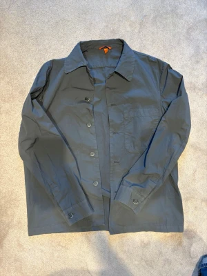 Grå overshirt från Barena - Stilren grå overshirt från Barena med klassisk krage, knappstängning och en bröstficka. Tillverkad i ett tunt, mjukt bomullstyg som ger en avslappnad look. Perfekt att bära öppen över en t-shirt eller stängd som lätt jacka.