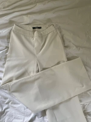 Vita kostymbyxor från Bik Bok - Säljer ett par stilrena vita kostymbyxor från Bik Bok. Byxorna har rak passform och hög midja, perfekta för en clean och modern look. Materialet känns mjukt och har en lätt stretch för extra komfort. Matcha med en skjorta eller crop top för en trendig outfit.