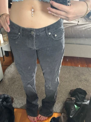 Mörk Grå raka jeans med låg midja - Säljer ett par grå jeans med låg midja och raka ben. Jeansen har klassiska fem fickor och stängs med knapp och dragkedja. Materialet är denim och färgen är tvättad grå, vilket ger en cool vintagekänsla.