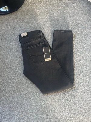 Jack & Jones jeans  - Snygga svarta slim fit jeans från Jack & Jones med klassisk femficksdesign och diskret logga på bakfickan. Jeansen har en modern passform och är tillverkade i stretchigt denim för extra komfort. Perfekta för en trendig och avslappnad stil.