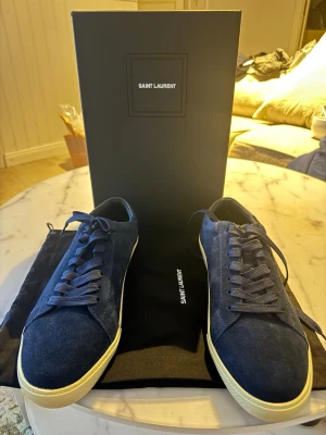 Suede sneakers mörkblå ysl - Säljer dessa fräscha oanvända suede skor. Helt ny säljer pga ingen användning samt rensar garderob. Modellen är perfekt för de som klär sig tyst.   Storlek 45. Ny pris: 5099-7499. Mitt pris: 3749kr  eftersom jag vill rensa snabbt garderoben. Pris kan diskuteras vid snabbaffär