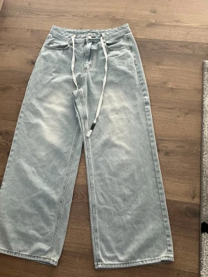 Ljusblåa wide leg jeans med snörning - Det här är ljust tvättade jeans med spets som inte kan tas bort. De kan dra åt midjan om det behövs, eller stoppas in i jeansen så att de inte syns. Thai är från Shein, märket Dazy, och om du bär S behöver du gå upp i storlek, så om du bär S-M kanske dessa passar dig bra.
