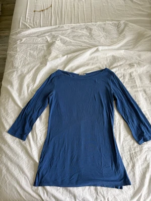 blå topp med trekvart från Intimissmi - En enkel och stilren blå topp med trekvartsärm och rund halsringning. Modellen är något längre och har en smal passform. Perfekt att matcha med jeans eller kjol för en clean look. Toppen är i storlek S och är ifrån INTIMISSMI. Packas och postas säkert! 💓