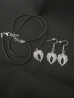 Halsband och örhängen med änglavingar - Handgjort set med halsband och örhängen med silverfärgade änglavingar. Halsbandet har ett svart läderliknande band och justerbart spänne. Örhängena har krokar i metall. Perfekt för dig som gillar unika smycken med symbolisk design.