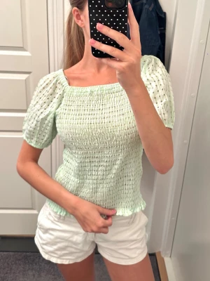 Supersöt rutig topp - Säljer en ljusgrön och vit rutig topp med puffärmar och volang, går att bära offshoulder 