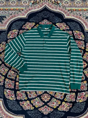 Grön randig långärmad polotopp - Grön långärmad polotopp med vita och gula ränder. Klassisk krage och relaxed fit, perfekt för en chill och stilren look. Passar till jeans eller kjol för en enkel men snygg outfit.