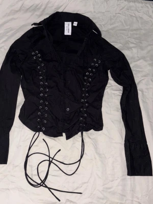 Alt alternativ goth gothic svart korsett skjorta - Helt ny men en öljett är borta, snug flattering fit! Sleeve length från axeln till ärmen är ca 60cm, waist ca 32cm. 100% bomull