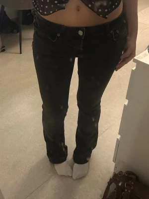 Svarta bootcut jeans med låg midja - Säljer ett par svarta bootcut jeans med låg midja och klassisk femficksmodell, från ZARA. Jeansen har en snygg tvätt och raka ben som går ut lite nedtill. Perfekta för dig som gillar en retro vibe och vill ha ett par stilrena jeans i garderoben. Har klippt upp jeansen, passar 150-157 cm