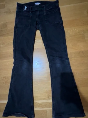 Svarta utsvängda jeans med fickor 🤍🖤 - Snygga svarta jeans med utsvängda ben och stora framfickor. Jeansen har dubbla knappar i midjan och markerade sömmar. Perfekta för dig som gillar retrostil och vill sticka ut med en cool siluett.
