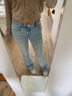 Ljusblå bootcut jeans - Säljer ett par ljusblå bootcut jeans med klassisk femficksdesign och normal midja. Jeansen har en avslappnad passform och är tillverkade i denim med lätt tvättad look. Perfekta för en casual och trendig stil.