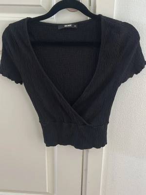 Svart omlottopp från Bik Bok - En svart omlott T-shirt från BikBok, använd fåtal gånger (har inga defekter)🌸  Storlek XS  Hör gärna av vid frågor eller önskan av fler bilder🤗