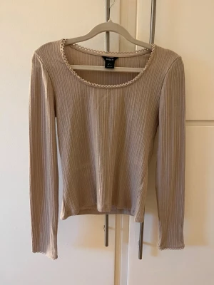 Beige ribbad långärmad topp - Tröja i ribbat tyg och liten spets i halsen