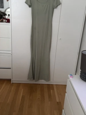 Ljusgrön långklänning med kort ärm - En enkel och stilren ljusgrön långklänning med rund halsringning och korta ärmar. Klänningen har en rak passform och är tillverkad i ett mjukt, stretchigt material som ger en bekväm känsla.