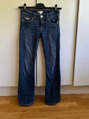 Bootcut jeans från Gina Tricot - HAR SMÅ DEFEKTER! Syns inge när de är på! Mörkblå bootcut jeans från Gina Tricot med klassisk femficksmodell och kontrastsömmar. Jeansen har en snygg tvättad look och silverfärgade knappar. Perfekta för dig som gillar en avslappnad men trendig stil.