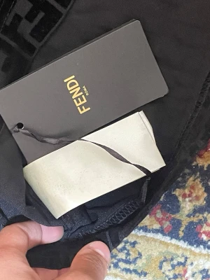 Svart Fendi klänning med logomönster - Supersnygg svart klänning från Fendi med ikoniskt logomönster över hela plagget. Klänningen har korta ärmar och en kroppsnära passform som ger en trendig siluett. Perfekt för dig som vill sticka ut med exklusiv design.